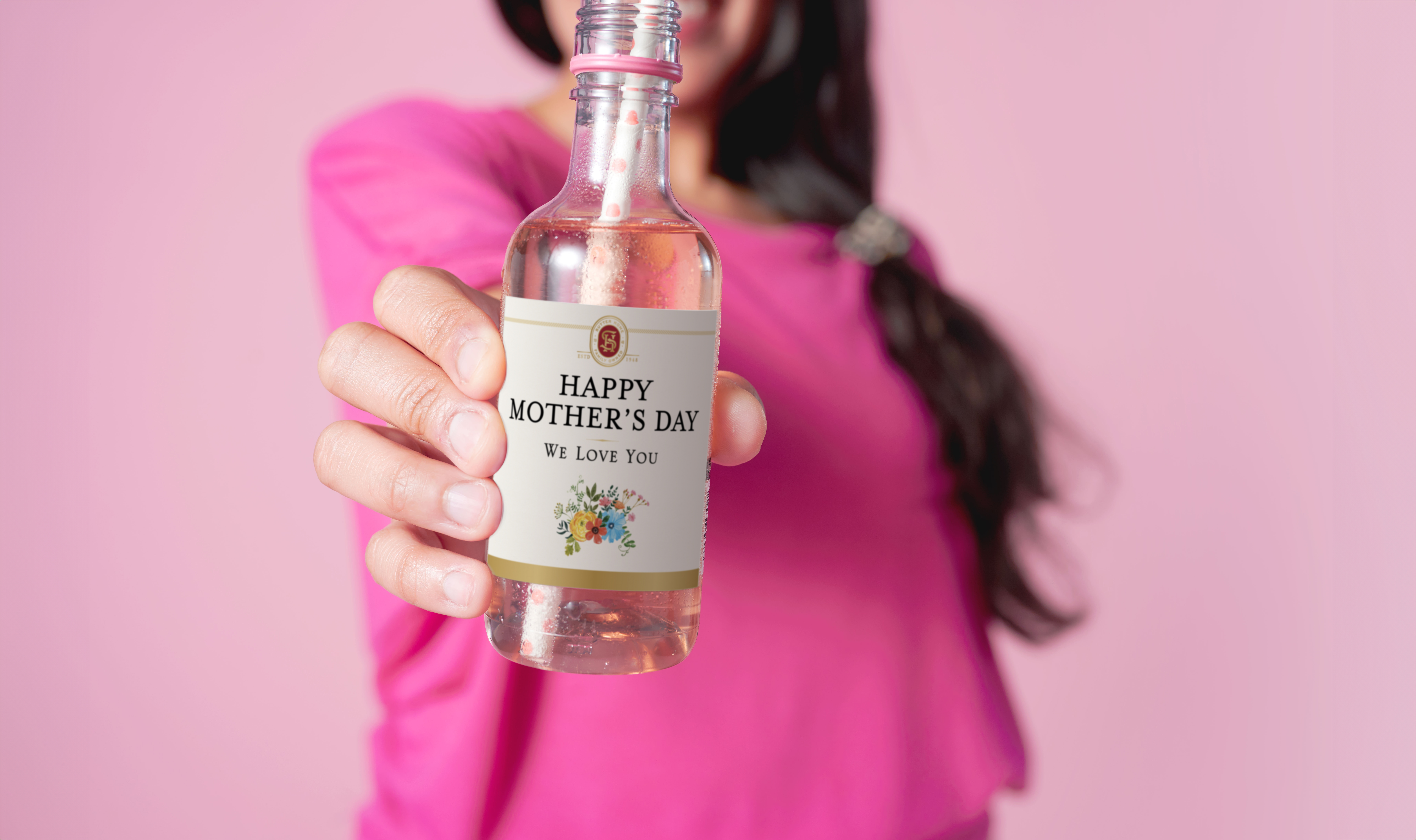 Woman wearing pink shirt and holding a Sutter Home Wine Mini Wine Bottle with custom sticker label