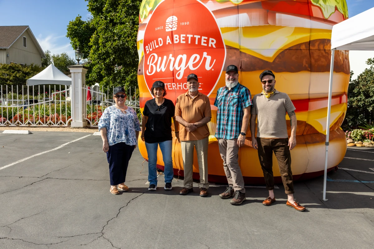 The 2026 build a better burger contestants standing in front of a blow up burger